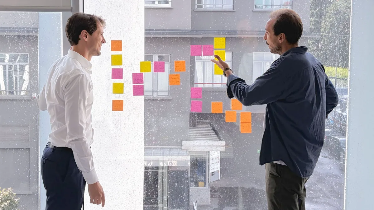 Due soci di Iusful davanti a una parete di post-it negli uffici di Milano Due soci di Iusful davanti a una parete di post-it negli uffici di Milano